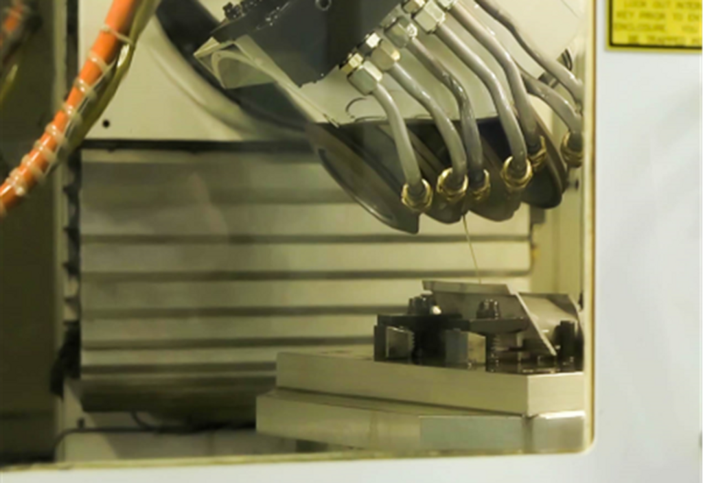 Turbine blade root form grinding setup with coolant nozzles and precision fixture, illustrating controlled grinding of heat-sensitive aerospace blade roots.